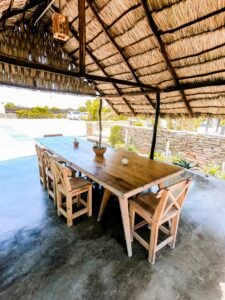 Wooden dining table and chairs under a thatched roof in Adicora, Venezuela.